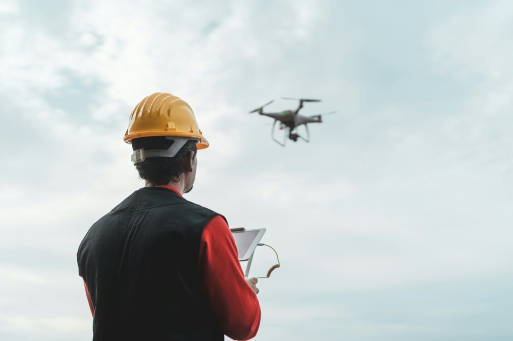 Male engineer monitoring construction site with drone - Cómo los Drones Están Transformando la Industria de la Construcción - RoCDrone - Facilitar la construcción con ayuda aérea