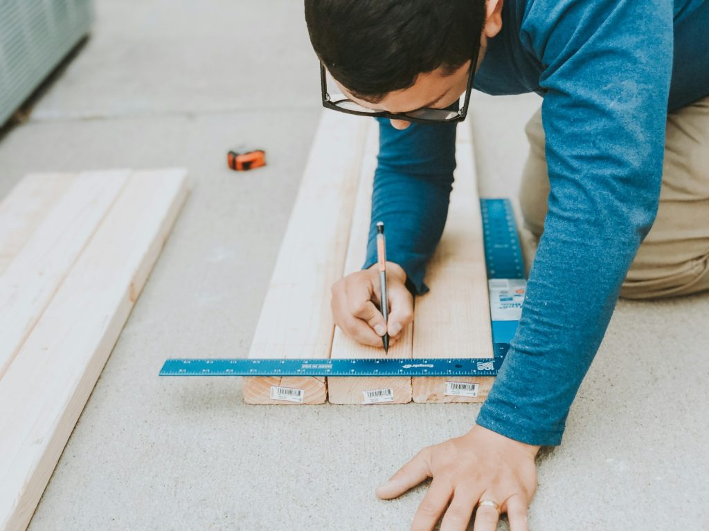 Man measuring wood to work on construction - Cómo los Drones Están Transformando la Industria de la Construcción - RoCDrone - Facilitar la construcción con ayuda aérea